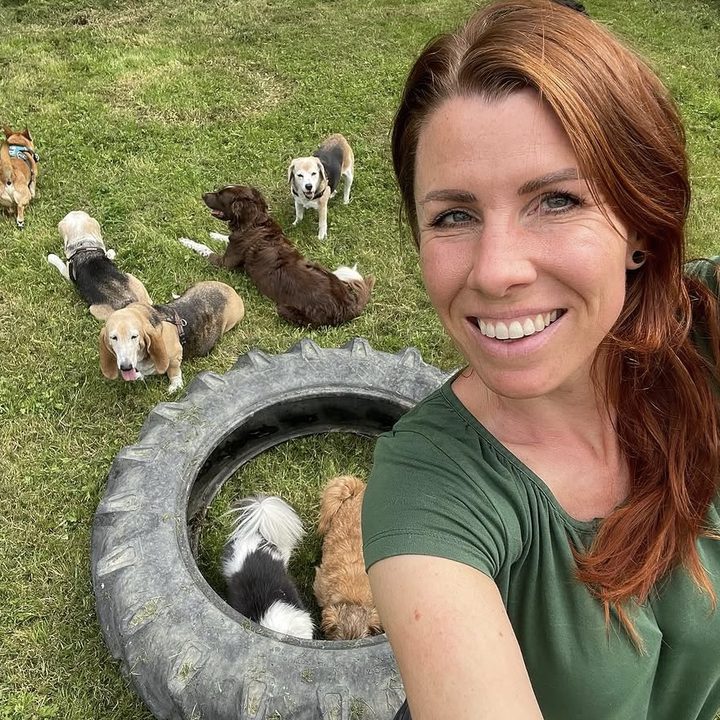 Linda maakt een selfie op het uitlaatveld, met de roedel en een grote autoband achter haar